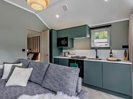 A kitchen with green cabinets and a sofa at Prion Spa, Llandyrnog