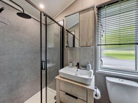 A bathroom with a shower, sink, mirror, and toilet at Prion Spa in Llandyrnog