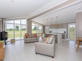 A living room with a sofa and kitchen area at Darwin Retreat in Wigton