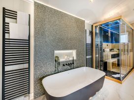 A bathroom with a bathtub and shower enclosure at The Sheraton Retreat in Wigton