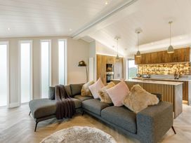 A living room with a sofa and kitchen area at The Sheraton Retreat in Wigton