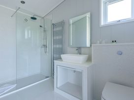 A bathroom with a shower, sink, mirror, and toilet at Wordsworth in Wigton