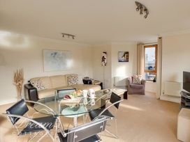 A living room with a sofa, dining table and television at Harbourside Apartment in Weymouth