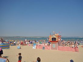 A crowded beach with umbrellas and a beach hut at Harbourside Apartment in Weymouth