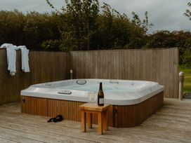 A hot tub with champagne and glasses on a wooden deck at Wellington in Wigton