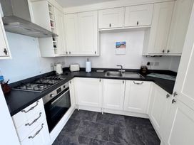 A kitchen with cabinets, stove, sink, and kettle at Ty Nain in Bodorgan