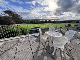 An outdoor seating area with a table and chairs overlooking a green landscape at Ty Nain in Bodorgan