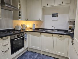 A kitchen with a kettle, toaster, sink and oven at Ty Nain Bodorgan