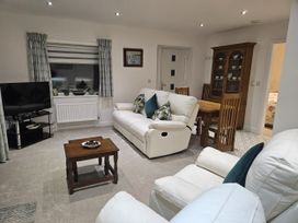 A living room with a sofa, television, and dining table at Ty Nain in Bethel