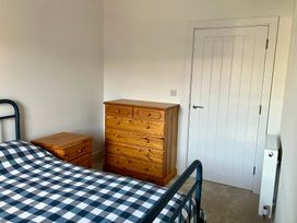 A bedroom with a bed, bedside table, chest of drawers, and door at 12 Brewhouse Place Weymouth