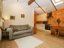 A living room with a sofa and kitchen area at The Log Cabin Corse near Gloucester
