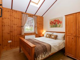 A bedroom with a bed and wardrobe at The Log Cabin in Corse near Gloucester