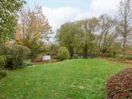 A garden with trees and a pond at The Log Cabin in Corse near Gloucester