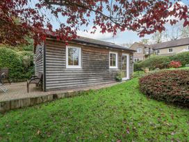 An outdoor view of a cabin with a patio and chair at The Log Cabin in Corse near Gloucester