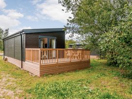 A cabin with a deck and surrounding greenery at Somersby Spa in Louth