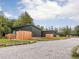 Several wooden cabins with gravel pathway and trees at Somersby Spa in Louth