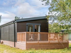 A cabin with a wooden deck and glass doors at Somersby Spa in Louth