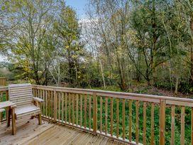 A deck with a wooden chair and trees in the background at Somersby Spa in Louth