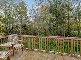An outdoor deck area with wooden railing and chairs at Somersby Spa in Louth
