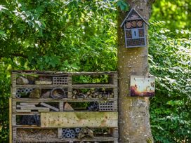 A wooden insect hotel on a tree with a sign in a garden at Wensleydale Aysgarth