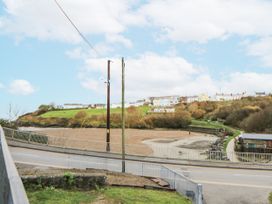 A view of houses on a hill with a road and trees at Fronglyd Aberporth