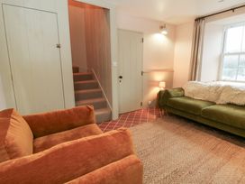 A living room with a sofa, armchair, and stairs at Fronglyd in Aberporth