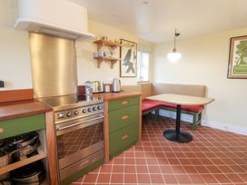 A kitchen with a stove and dining area at Fronglyd Aberporth