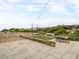 A garden with a table and chairs overlooking a hillside at Fronglyd Aberporth