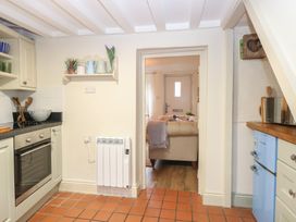 A kitchen with various appliances and view of living area at Beeble Cottage in Fakenham