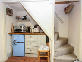 A small kitchen area with appliances and a staircase at Beeble Cottage in Fakenham