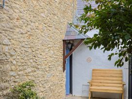 An outdoor area with a stone wall and a wooden bench at Vine Cottage in Burton Bradstock