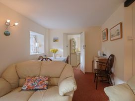 A living room with a sofa and dining table at Vine Cottage in Burton Bradstock