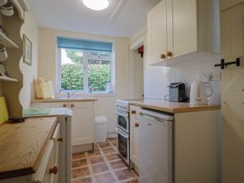 A kitchen with cabinets and appliances at Vine Cottage in Burton Bradstock