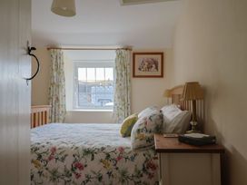 A bedroom with a bed and nightstand at Vine Cottage, Burton Bradstock
