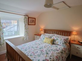 A bedroom with a bed and window at Vine Cottage in Burton Bradstock