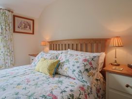 A bedroom with a bed and bedside lamp at Vine Cottage in Burton Bradstock