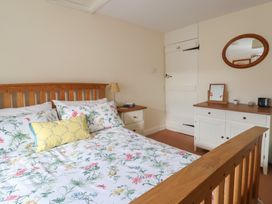 A bedroom with a bed and furniture at Vine Cottage in Burton Bradstock