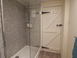 A bathroom with a shower and a door at Vine Cottage in Burton Bradstock