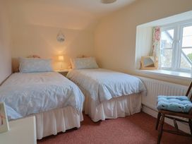 A bedroom with two beds and a window at Vine Cottage in Burton Bradstock