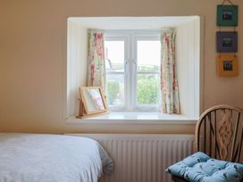 A bedroom with a window and mirror at Vine Cottage in Burton Bradstock