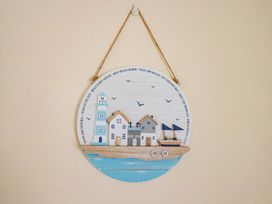 A decorative plaque featuring a lighthouse and houses at Vine Cottage in Burton Bradstock