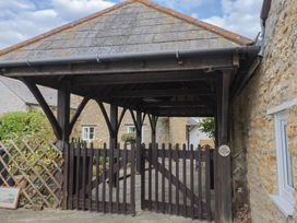 An outdoor area with a wooden gate and stone walls at Vine Cottage in Burton Bradstock