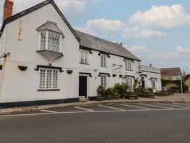 A pub with a sign and outdoor seating at The Anchor Inn in Burton Bradstock