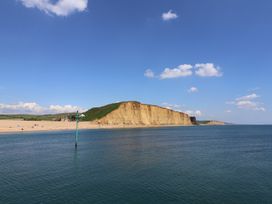 A beach with a cliff and ocean at Vine Cottage in Burton Bradstock