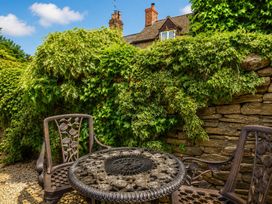 A garden with a stone wall and metal table and chairs at 29 Spring Street in Chipping Norton