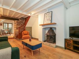A living room with a sofa, armchair, coffee table, and television at 6 Priory Lane Burford