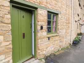 A green door and window on a stone wall at 6 Priory Lane in Burford