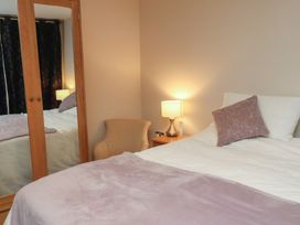 A bedroom with a bed, lamp, mirror, and chair at Farriers Yard in Whitby