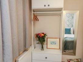 A wardrobe with a vase of flowers and a mirror at Farriers Yard in Whitby