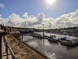 A view of boats in the water by the pier at Farriers Yard in Whitby